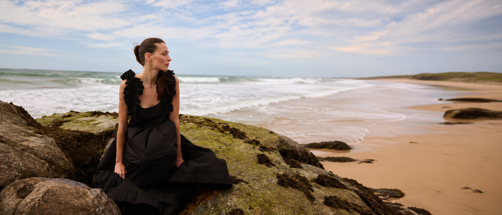 Woman wearing an elegant black dress by the coast